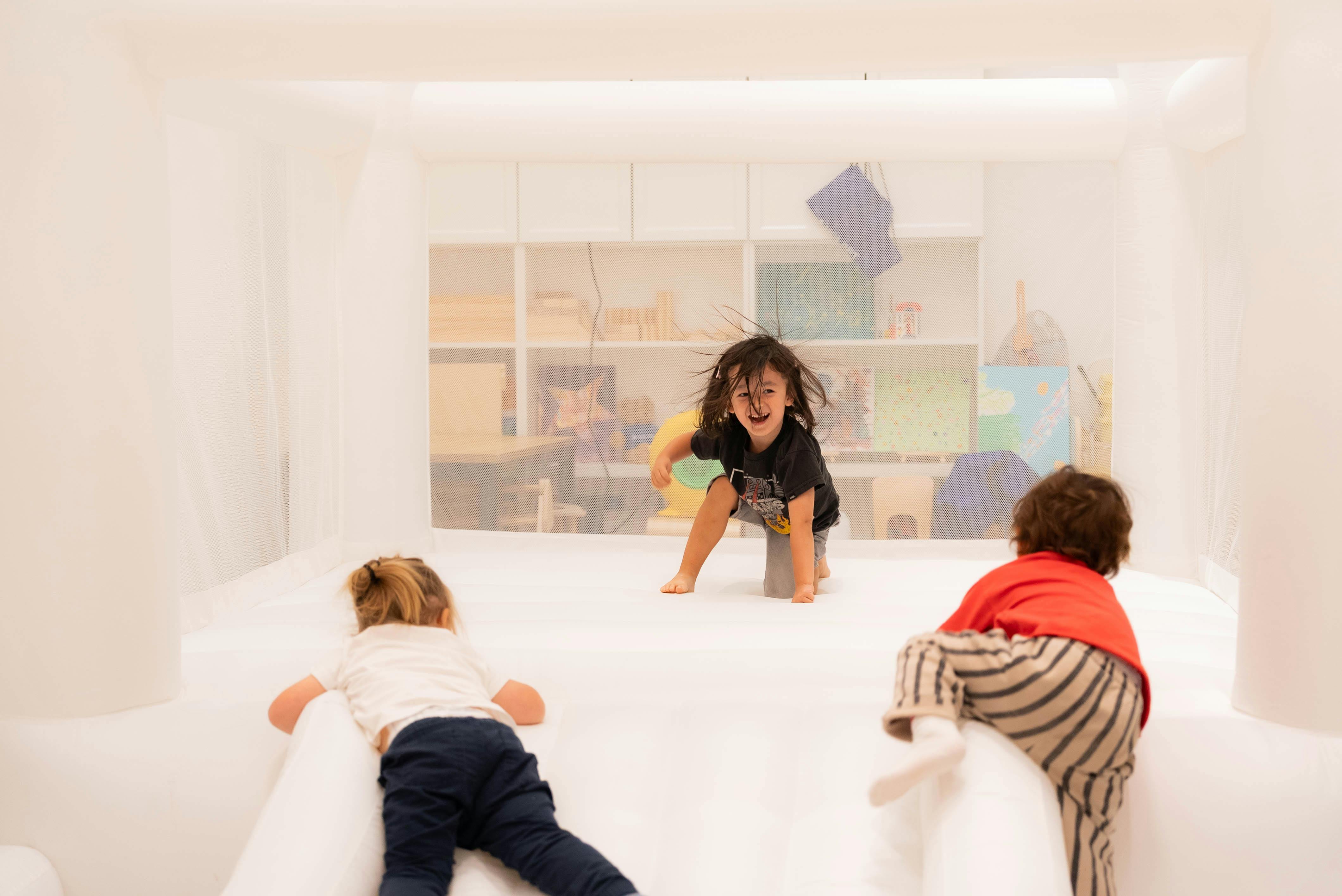 Three children playing on a white bouncy castle