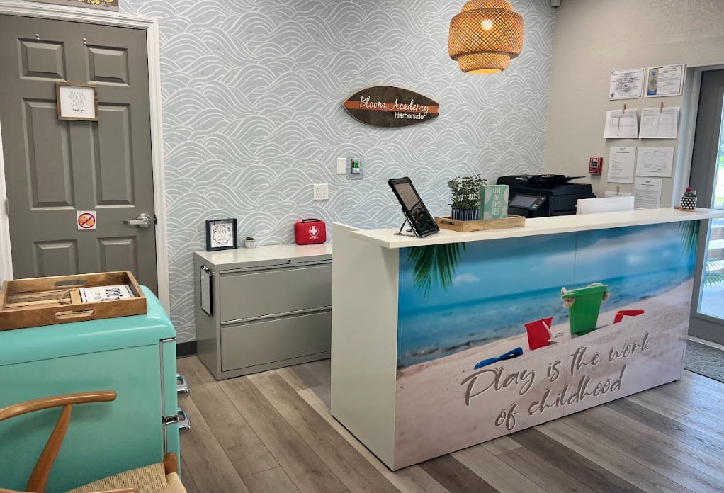 Reception desk with a beach scene graphic and a wooden sign on a light blue cabinet