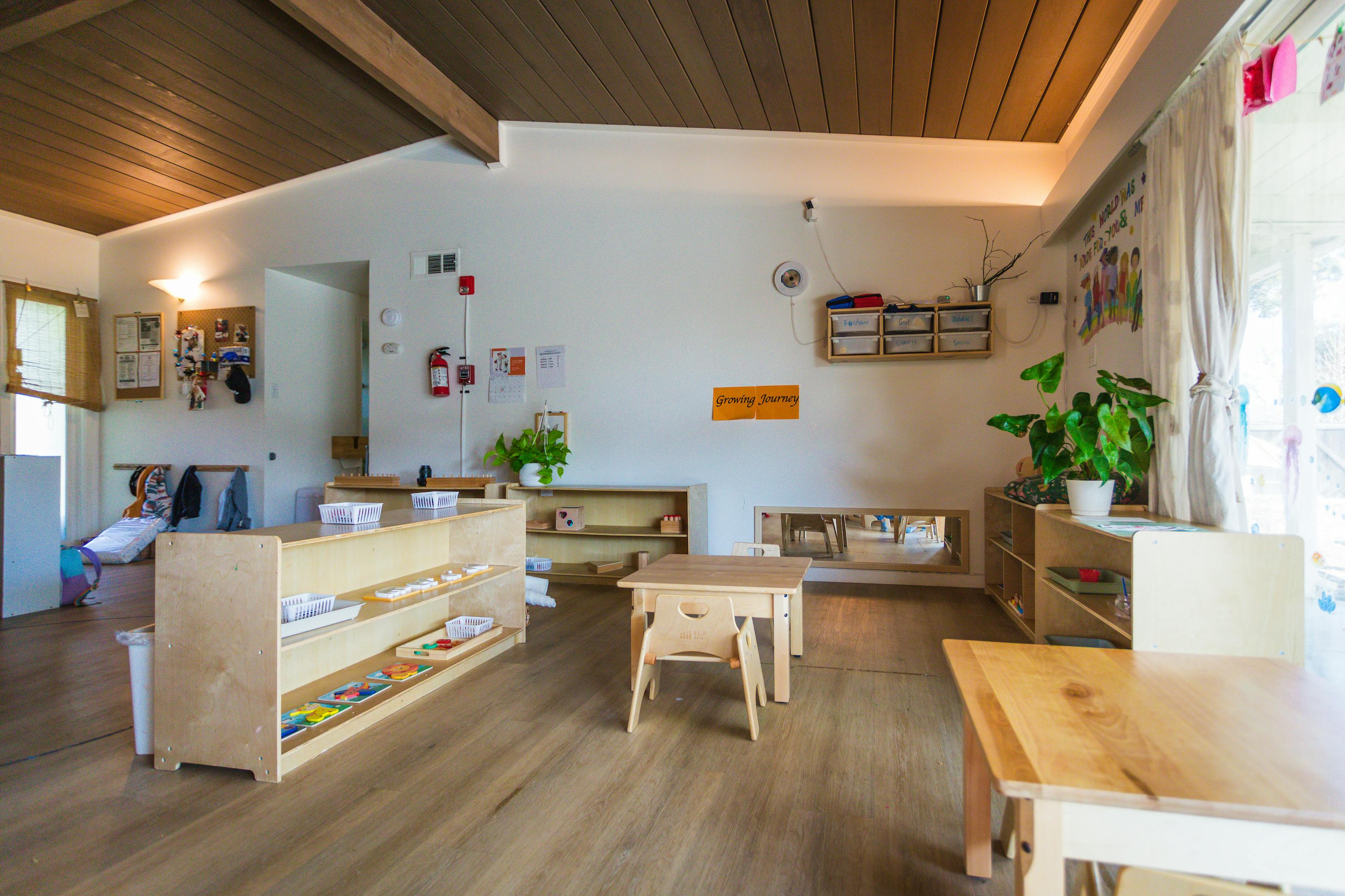 Empty classroom with small wooden tables and shelves
