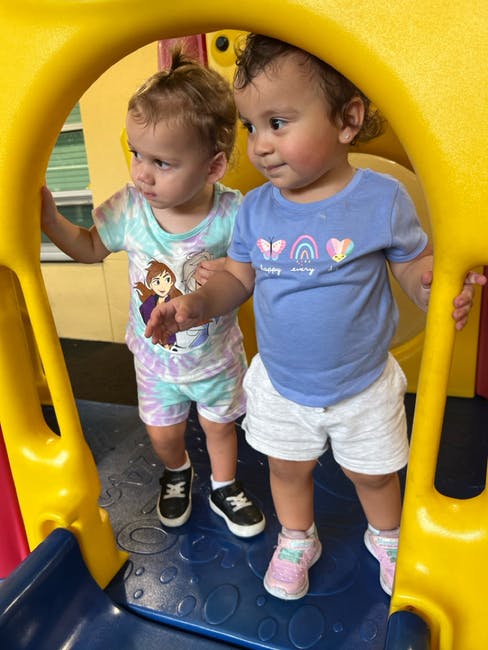 Two children standing on a blue play structure