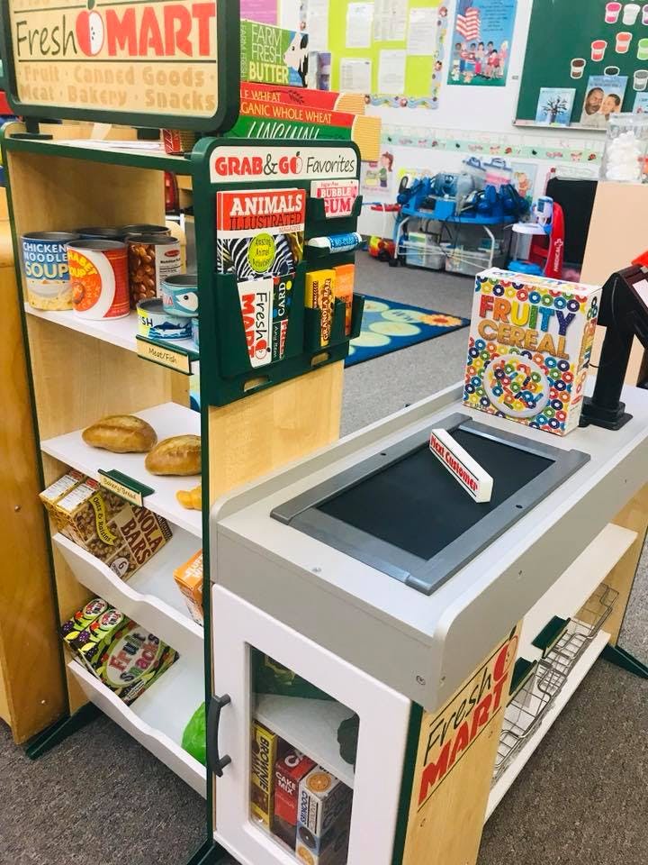 Play grocery store with shelves of toy food and a checkout counter