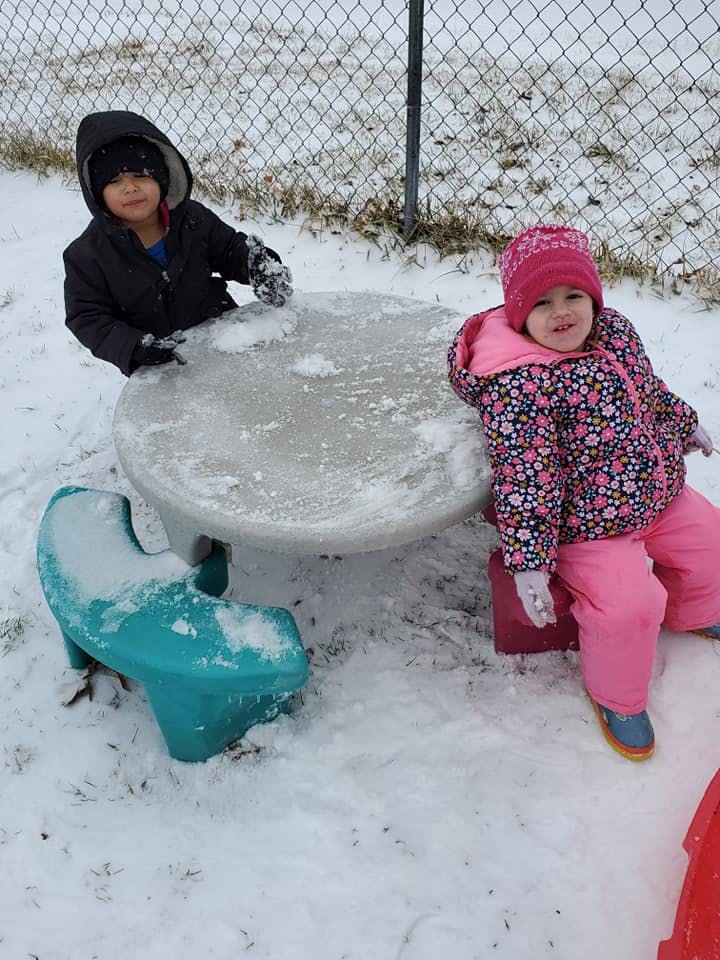 Two children playing in snow around a small table