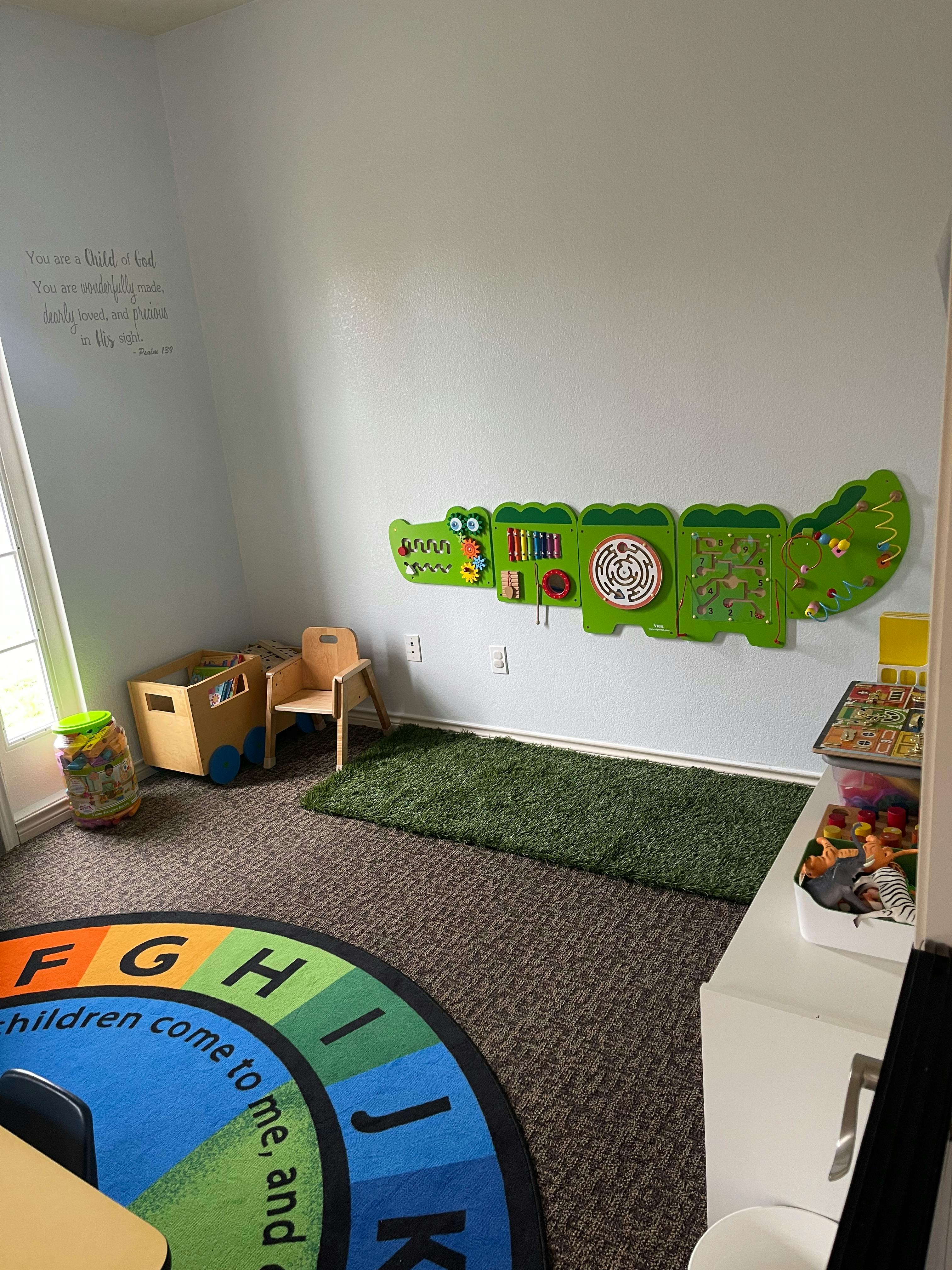 Children's play area with a green alligator activity board on the wall