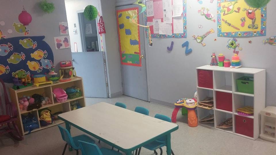 Classroom with small table and chairs, shelves with toys, and decorations on walls