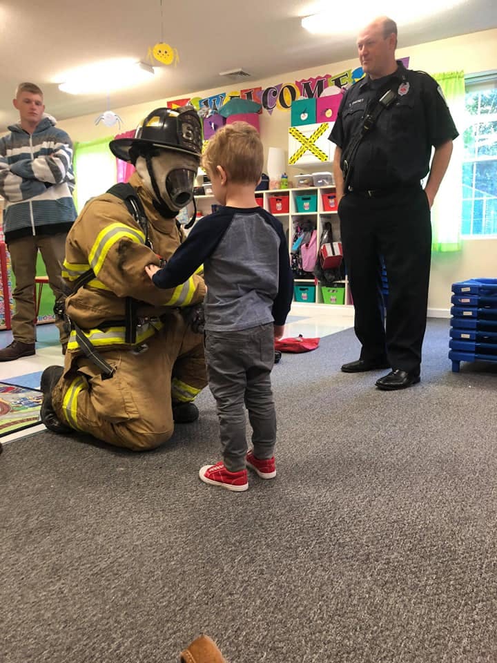 Firefighter in full gear kneeling and interacting with a child