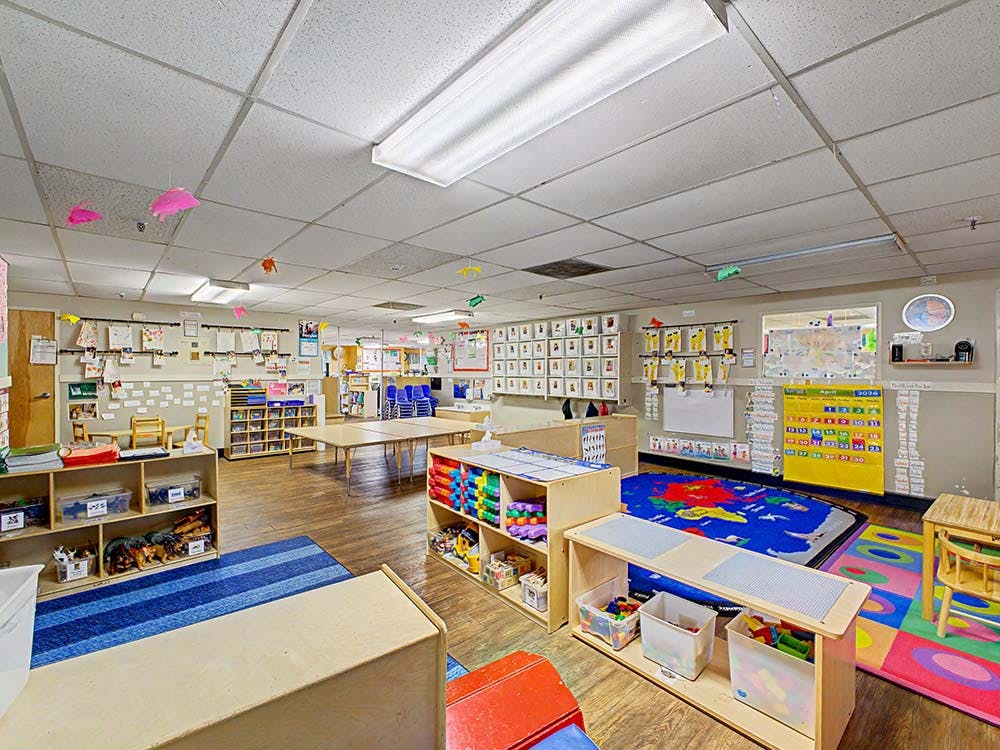 Colorful and organized classroom with tables, shelves, and rugs