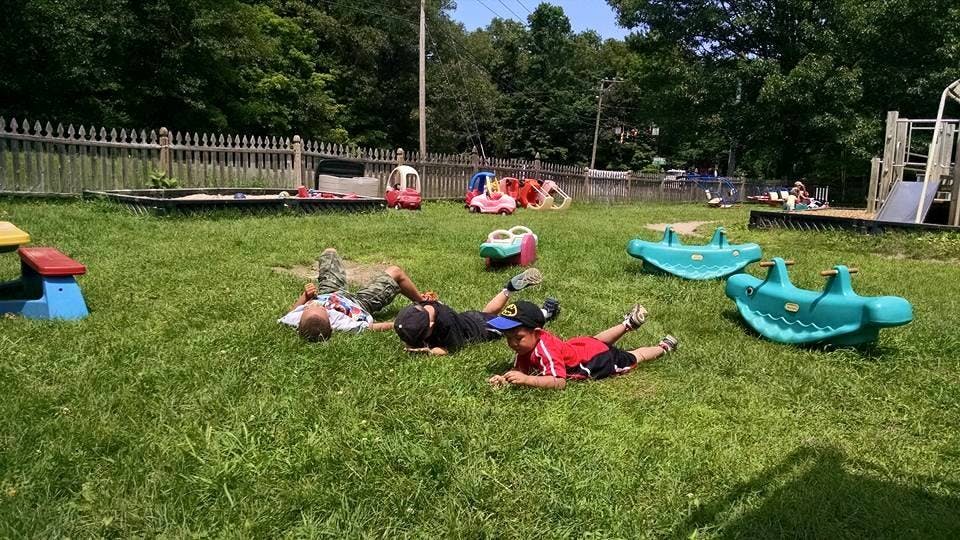Three children lying on grass in a playground