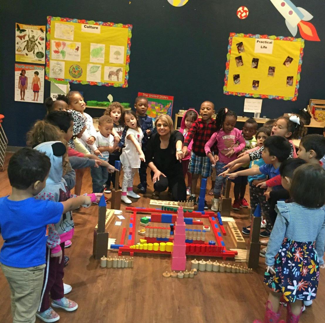 Adult and children gathered around a construction toy in a classroom