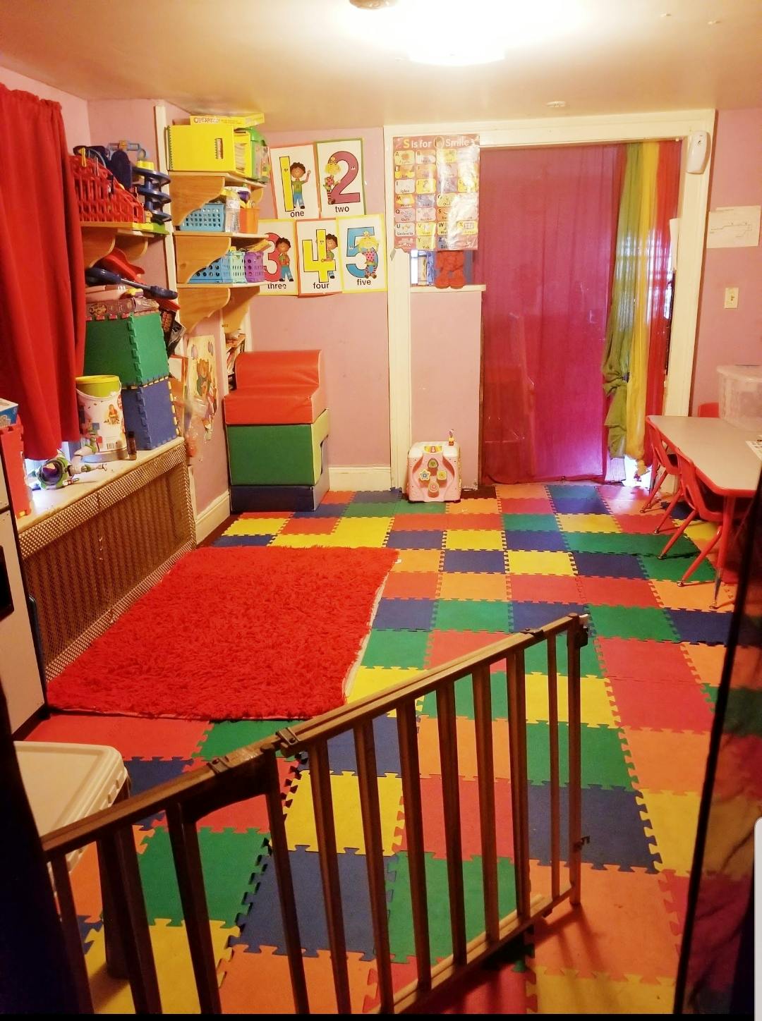Playroom with colorful floor mats, shelves, and a small table