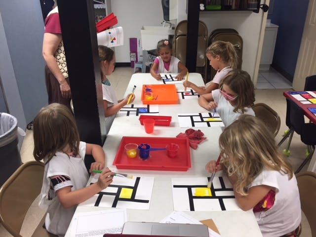 Children painting geometric patterns at a table