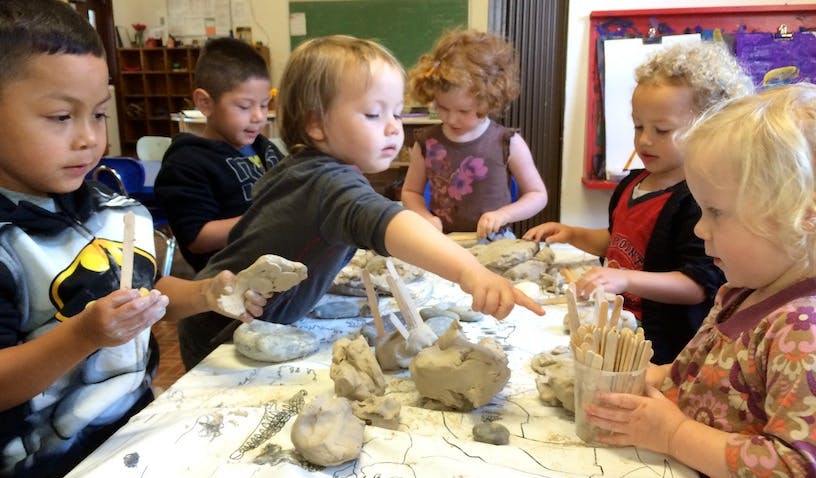 Children working with clay and other materials at a table