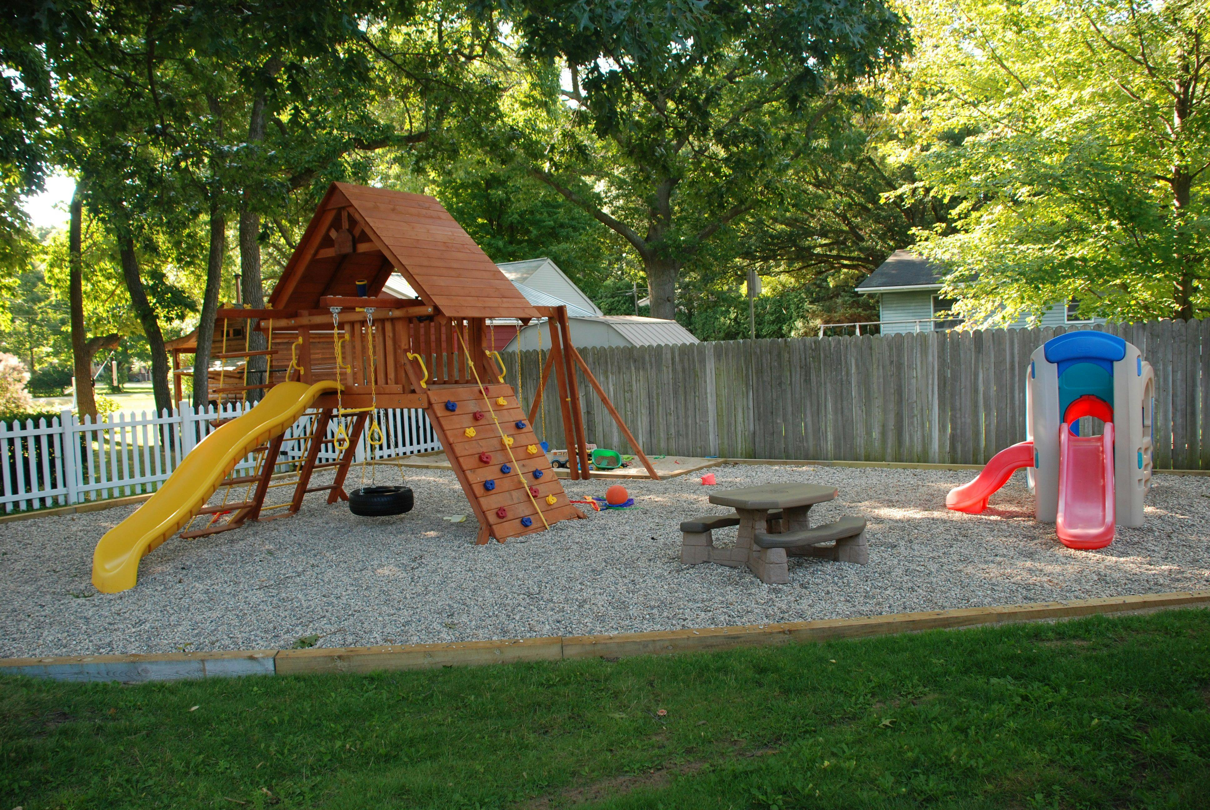 Playground with wooden playset, yellow slide, and small picnic table