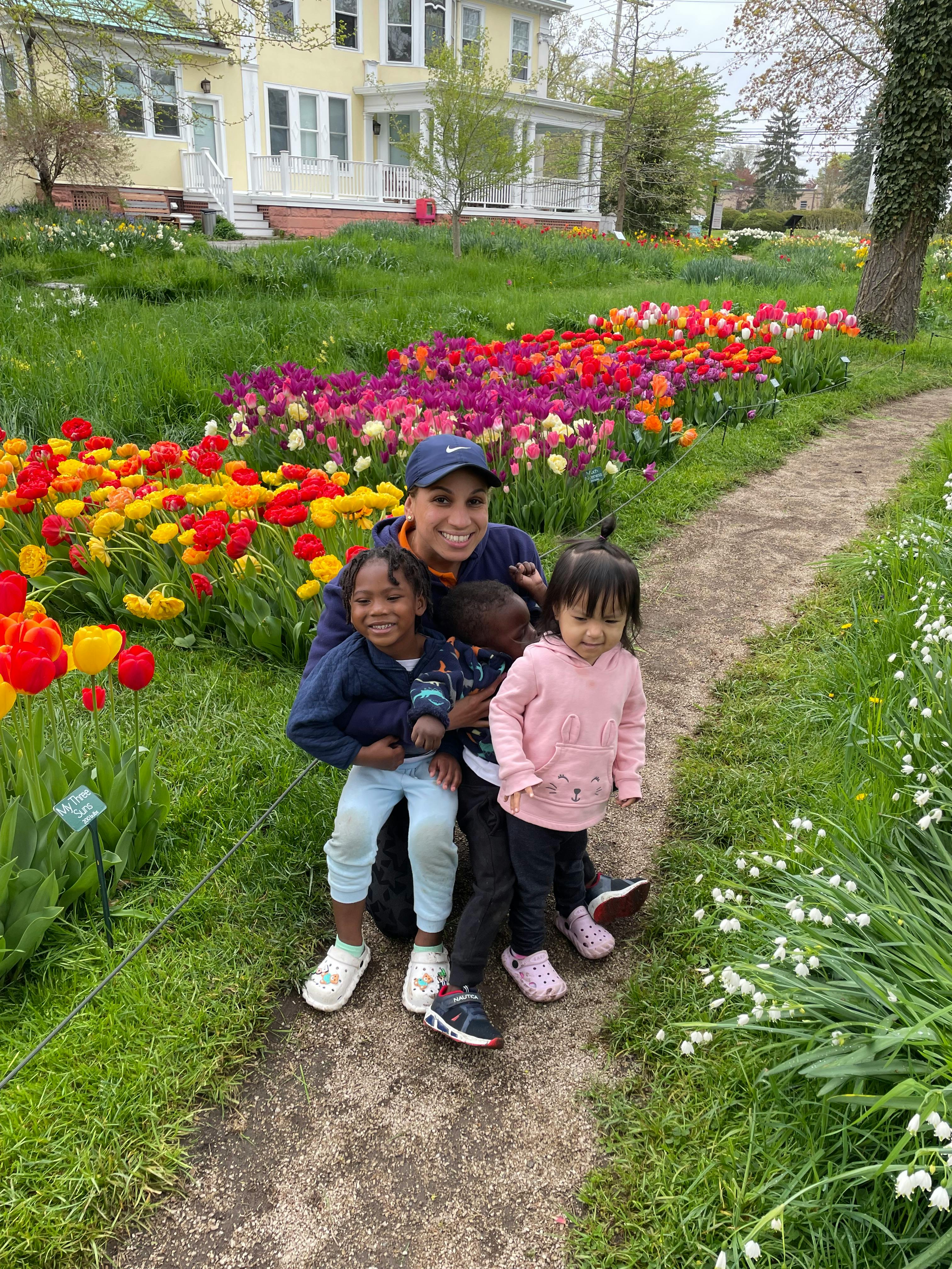 Person with three children in a garden with colorful tulips
