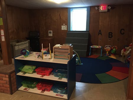 Classroom with a colorful rug, shelves, and window