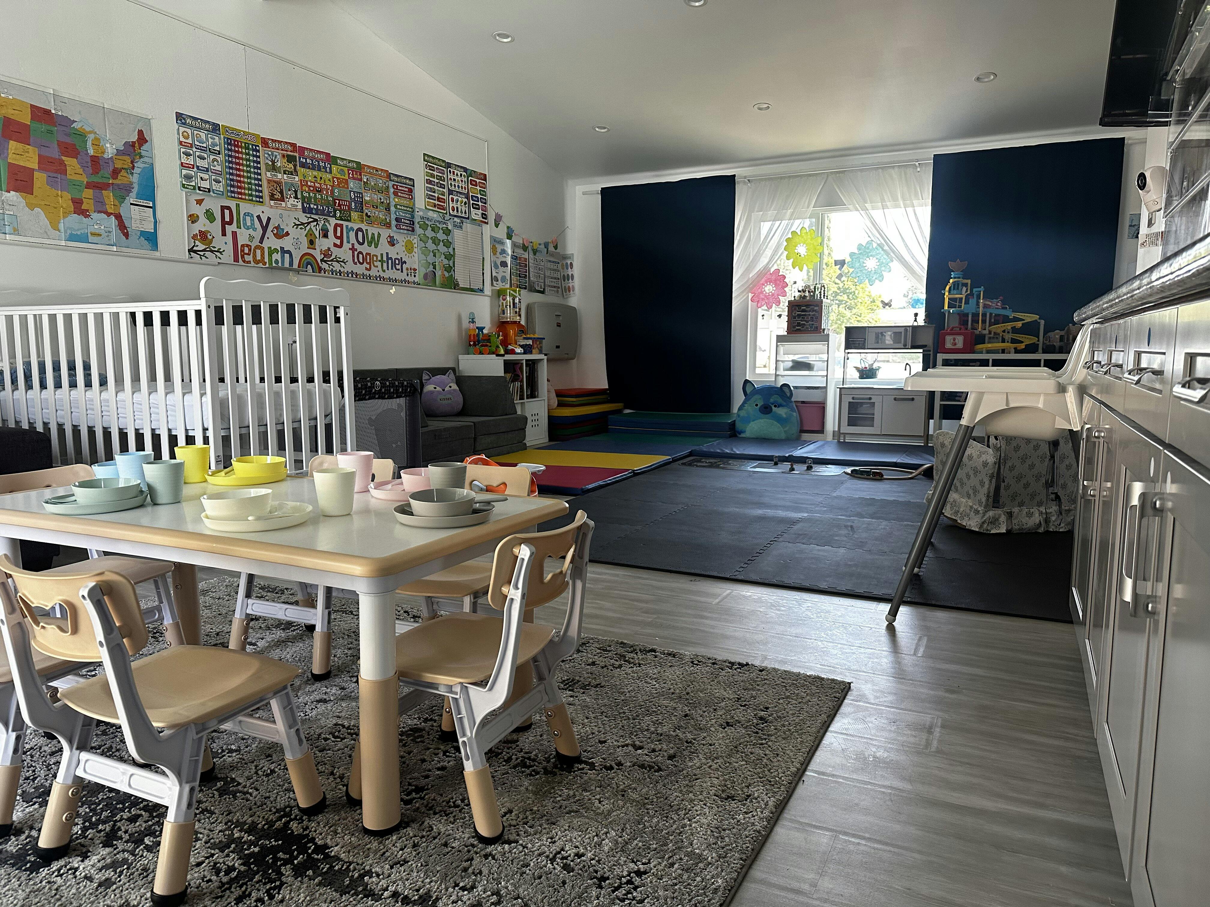 Children's play area with small table and chairs, cribs, and play mats