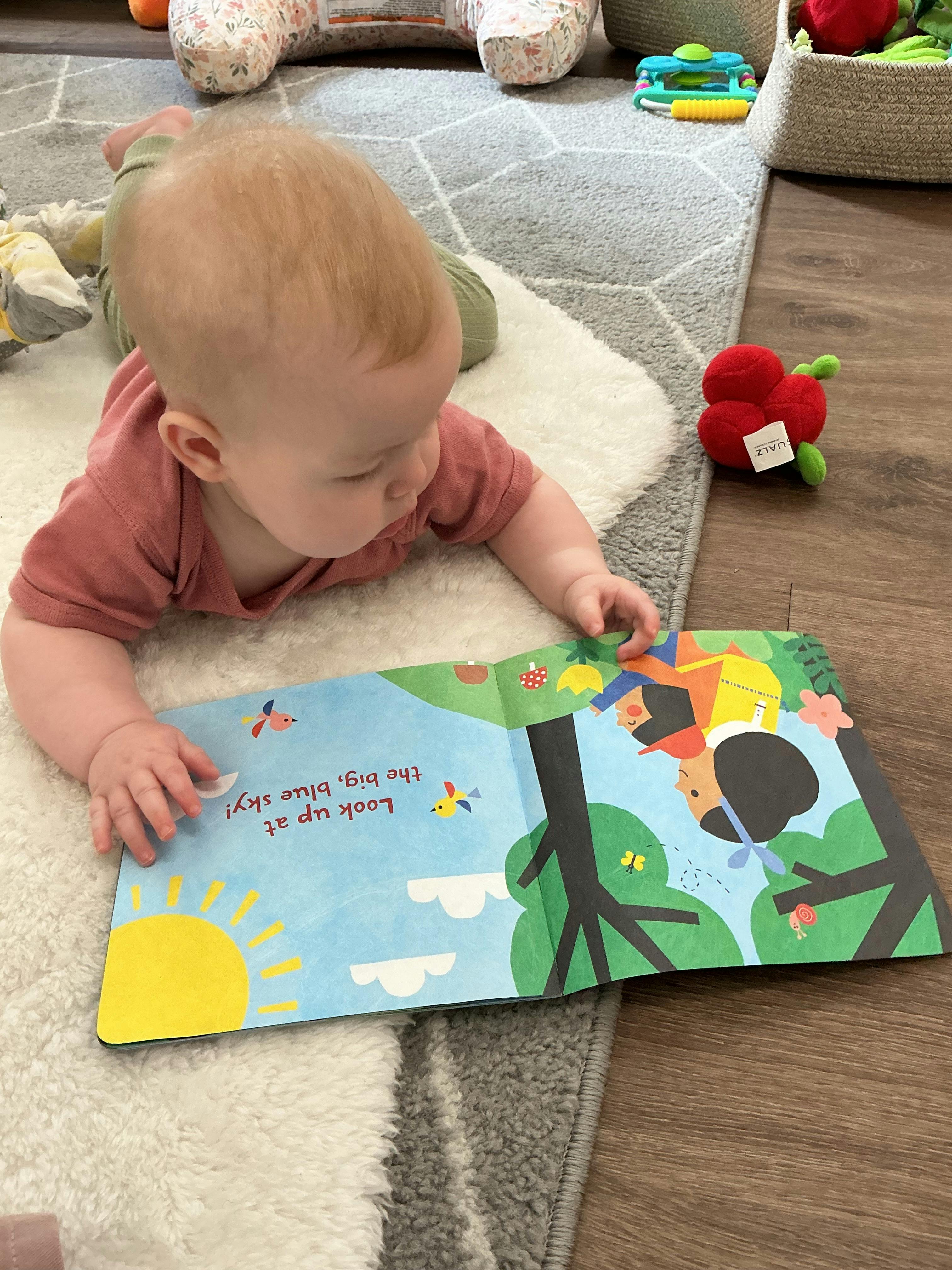 Child on a white fluffy rug, looking at an open picture book