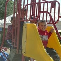 Child on a yellow slide with another child in the background