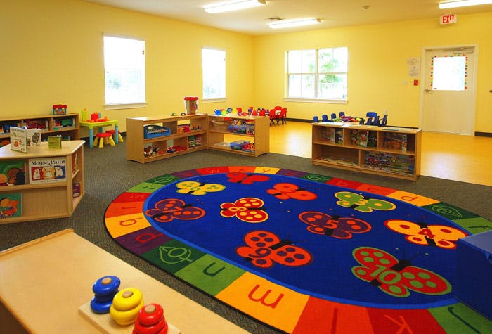 Classroom with colorful rug, shelves, and small tables