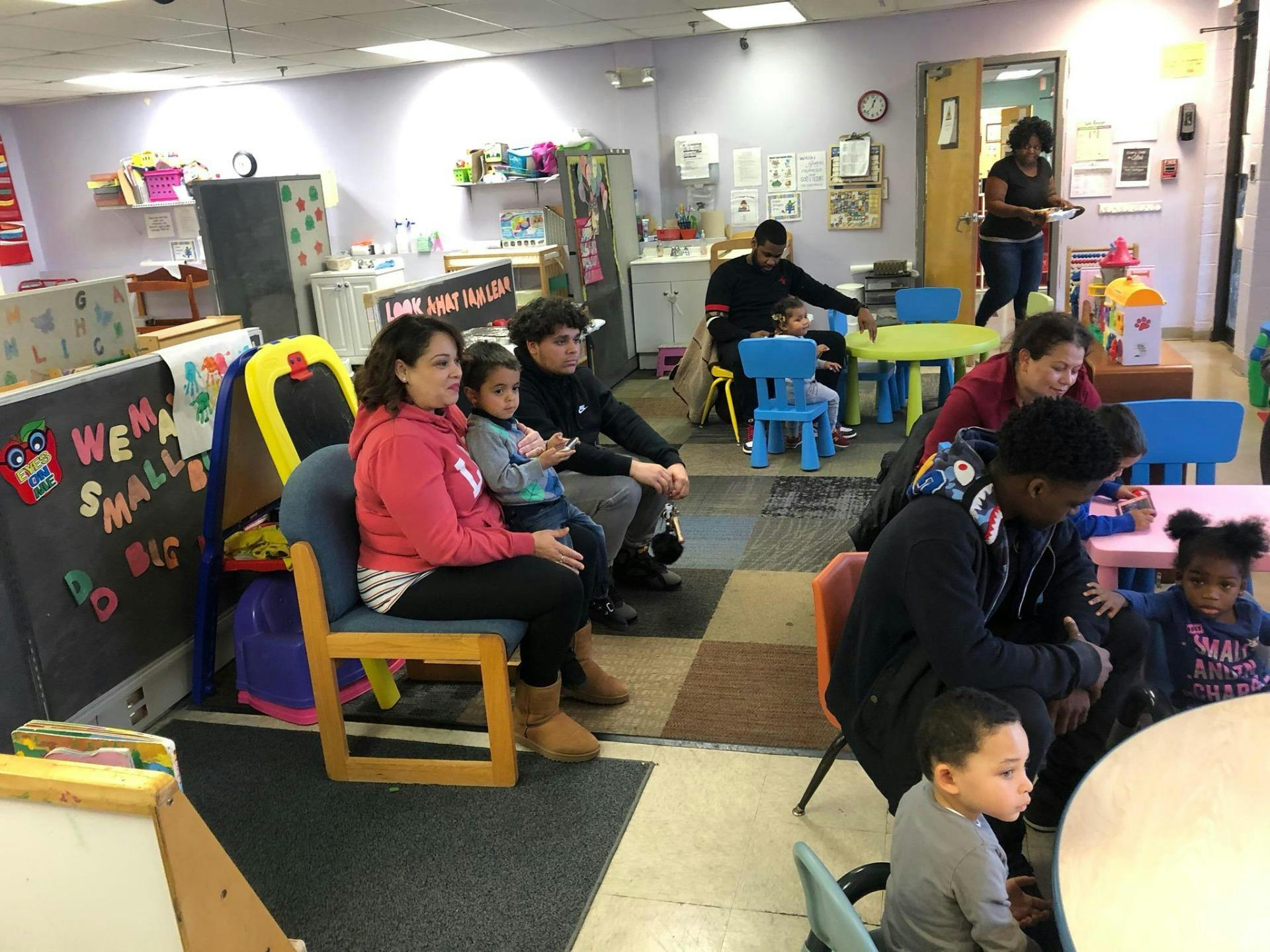 multiple people and children gathered in a classroom
