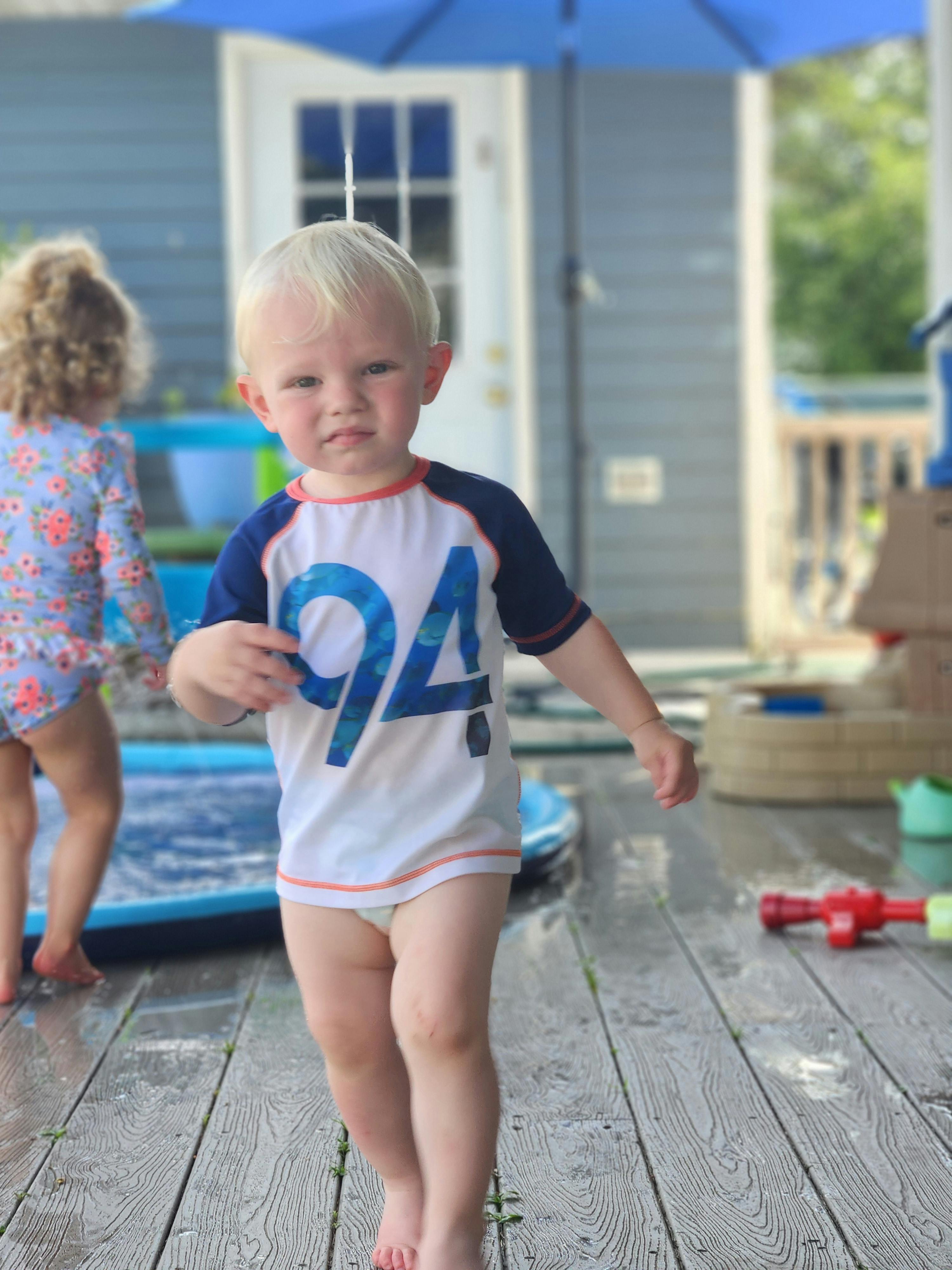Child in a shirt with "94" on it walking on a wet deck