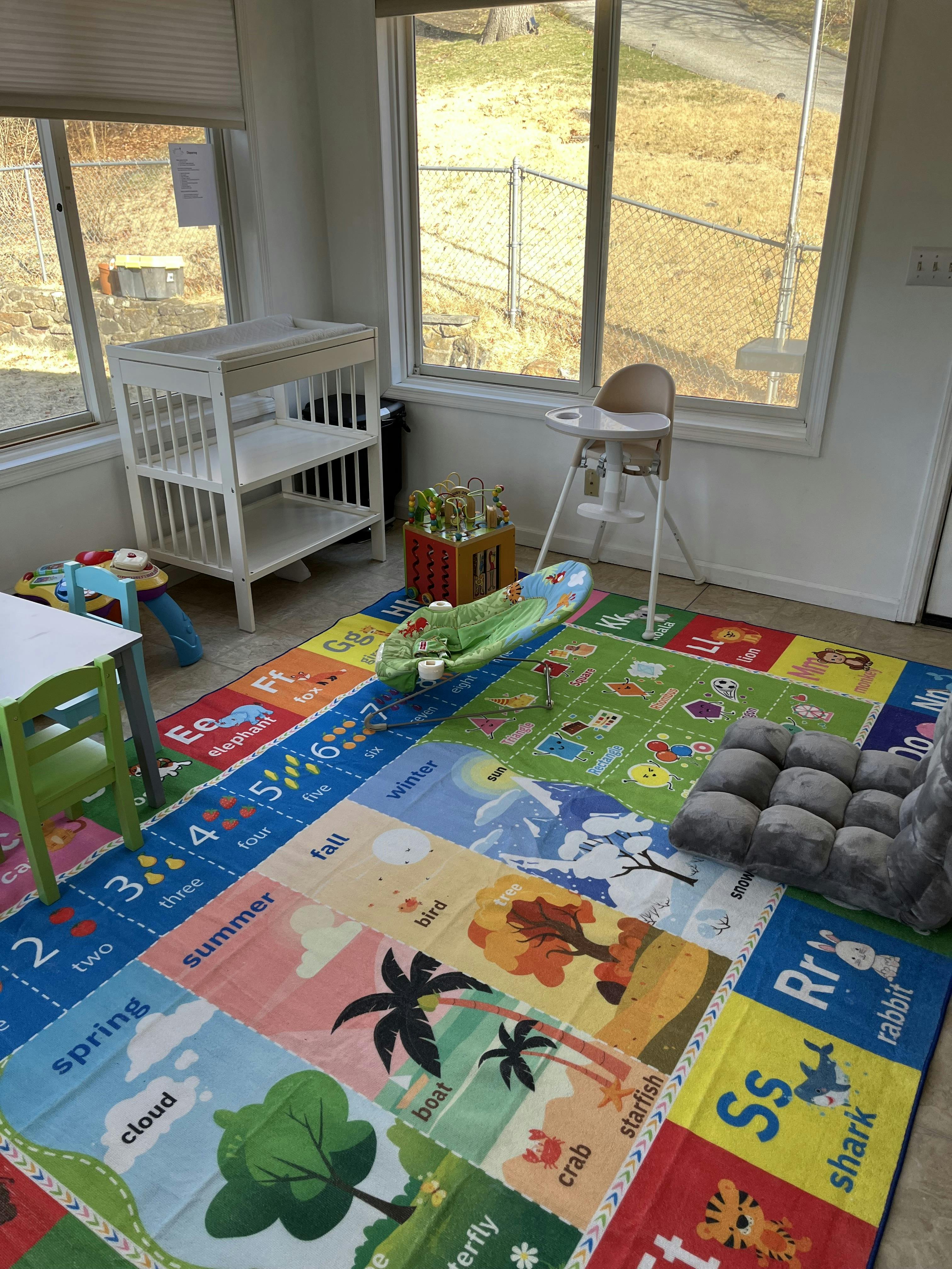 Playroom with a colorful alphabet and number rug, changing table, and high chair