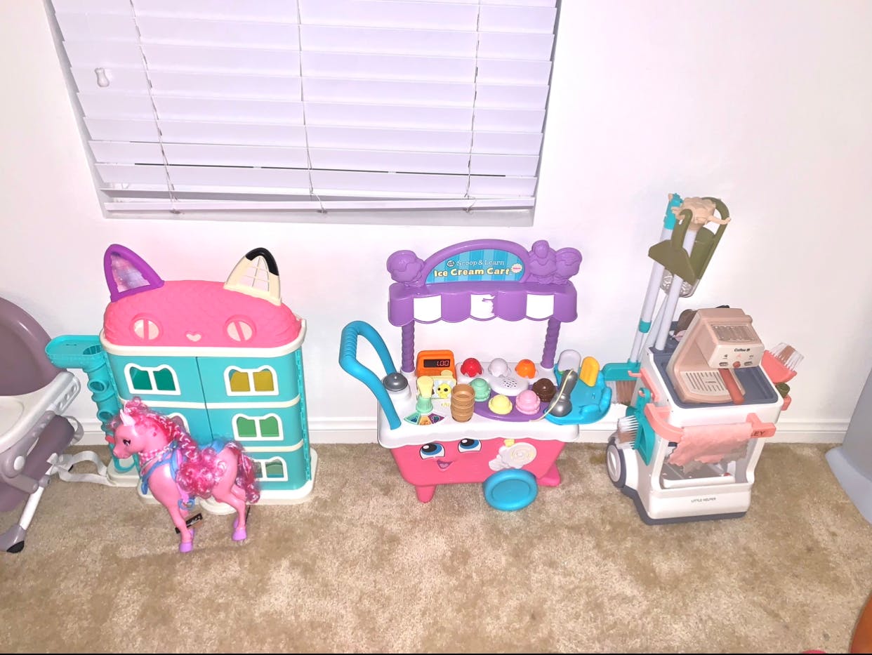 Children's toys including a dollhouse, ice cream cart, and shopping cart