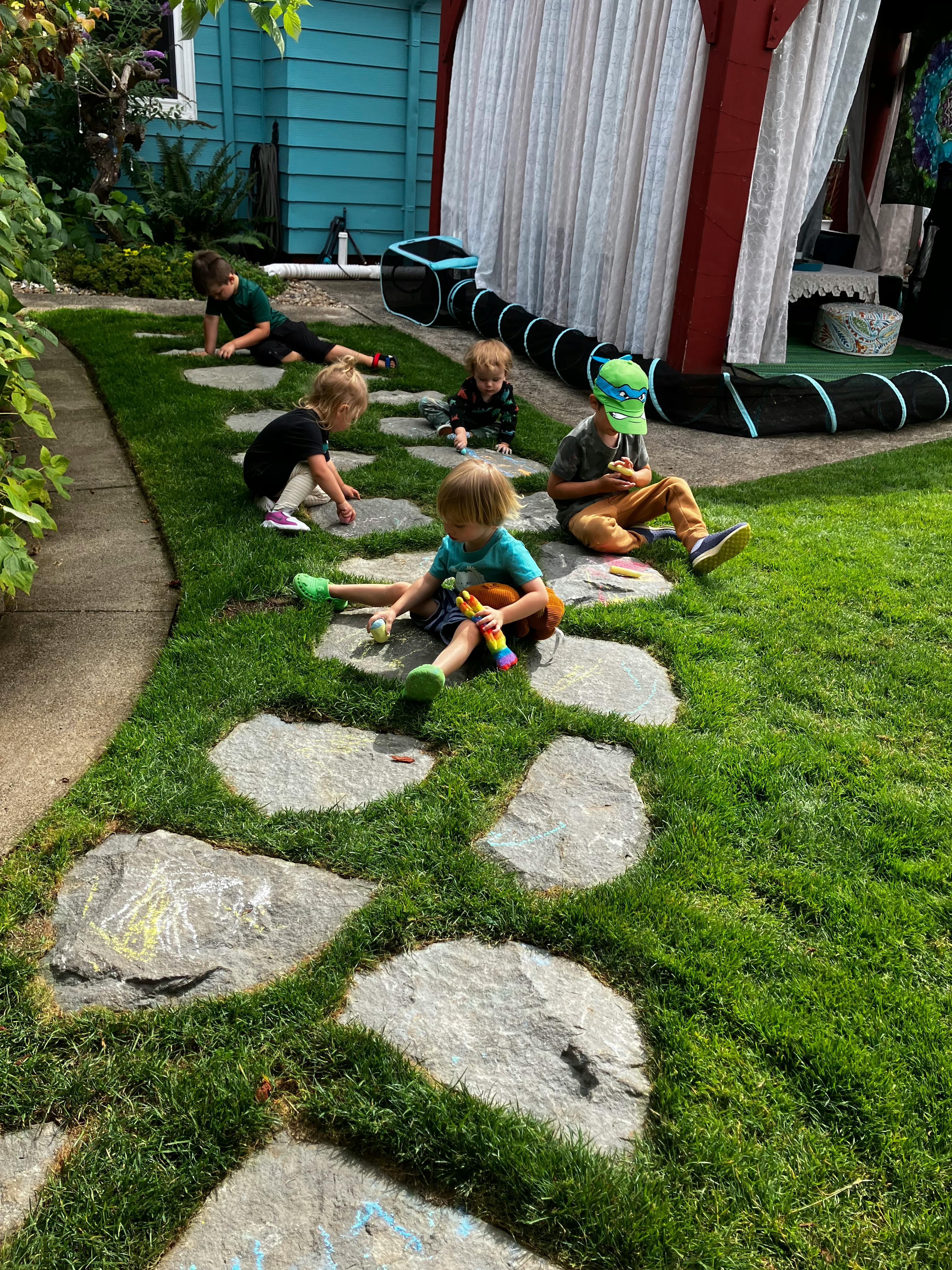 Children drawing with chalk on stone garden path