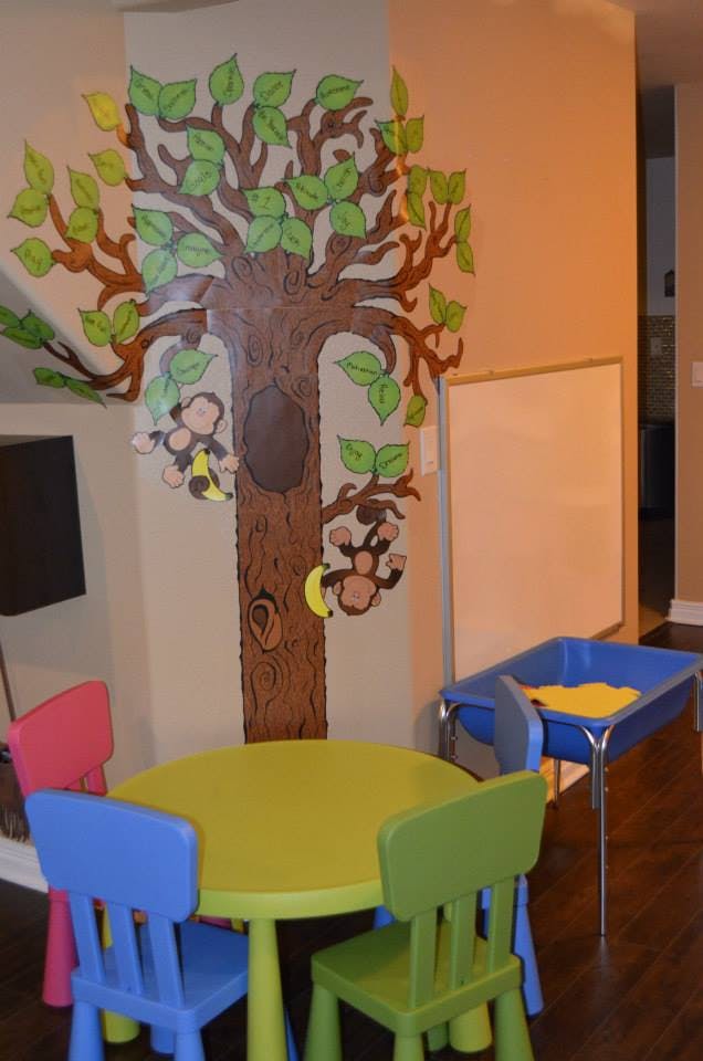 Tree mural with monkeys, small table and chairs, and a sand table