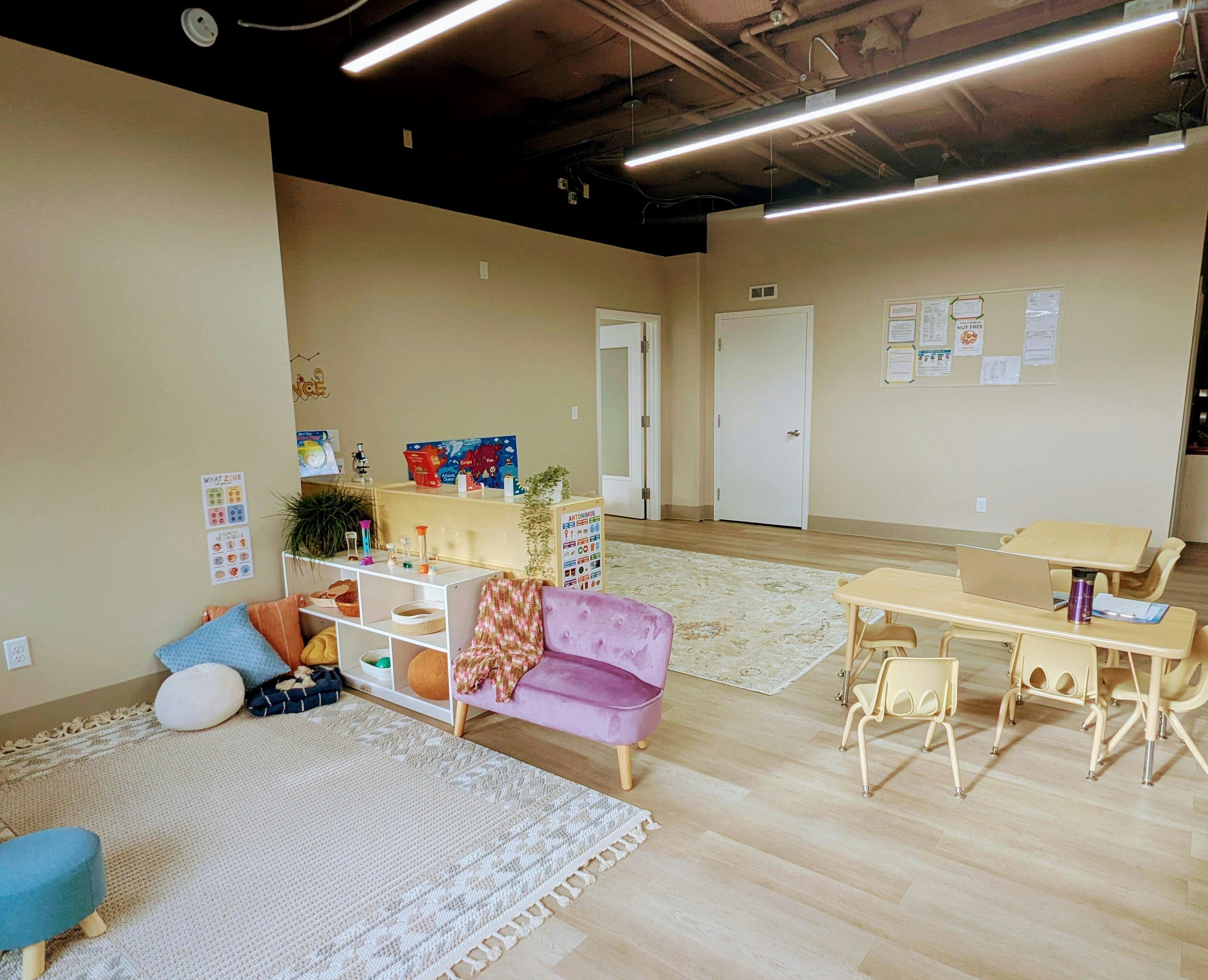 Playroom with small purple couch, shelves, and children's tables and chairs