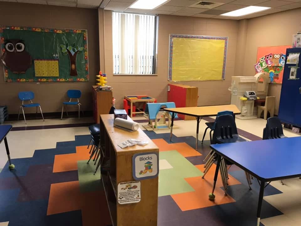 Empty classroom with small tables and chairs, colorful floor tiles