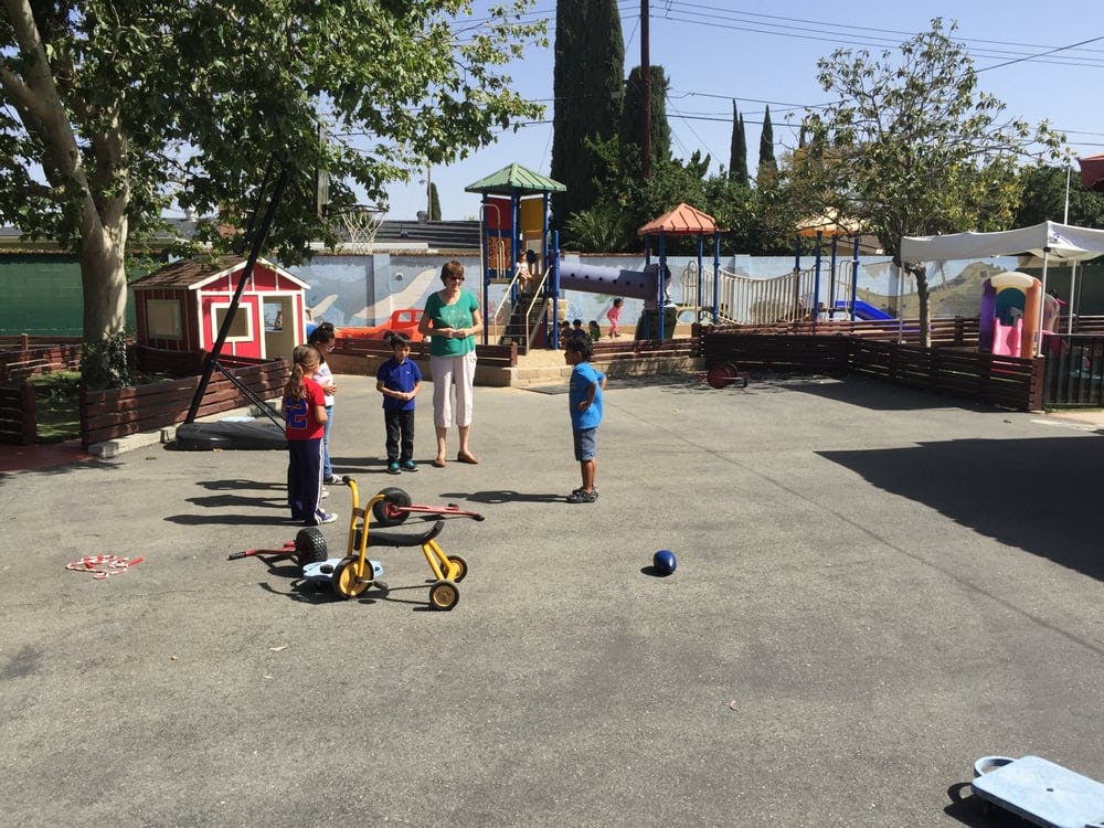 Adult and children on a playground with play equipment