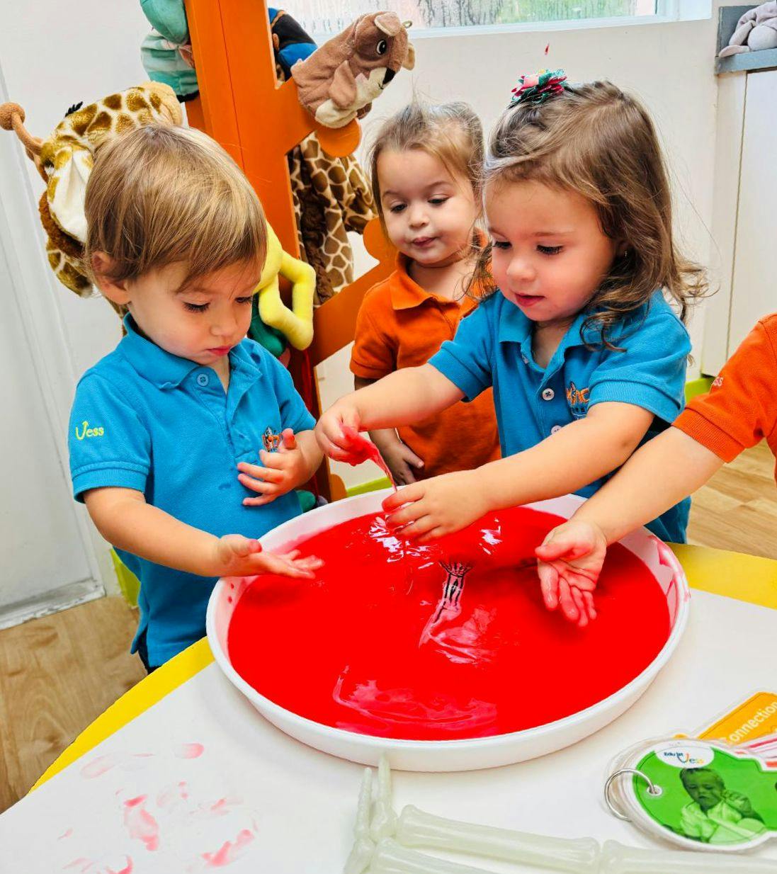 Children playing with red liquid in a white bowl