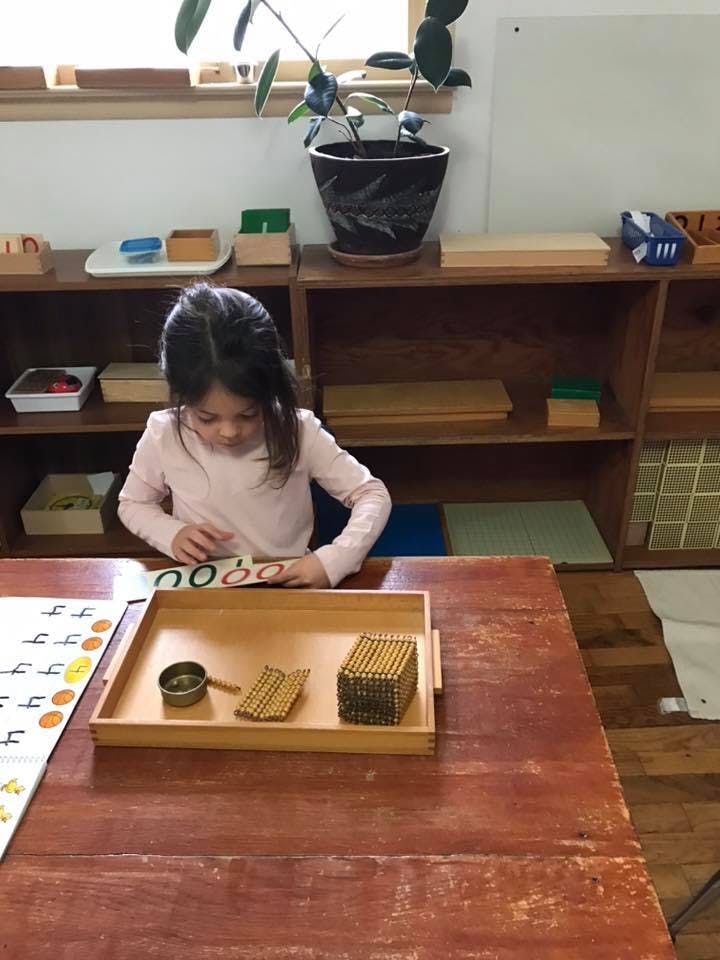 Child sitting at a table, looking at a learning activity