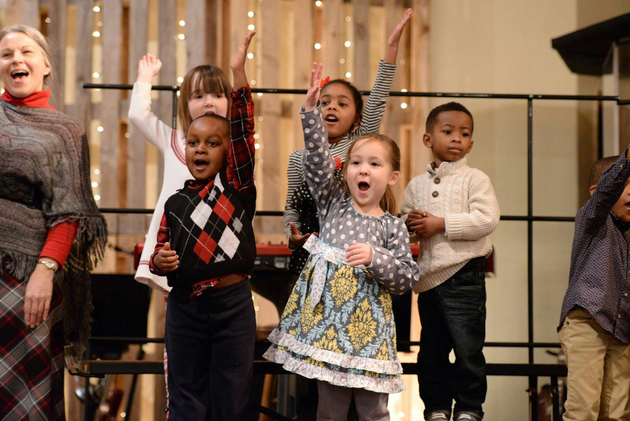 Adult and children singing with hands raised