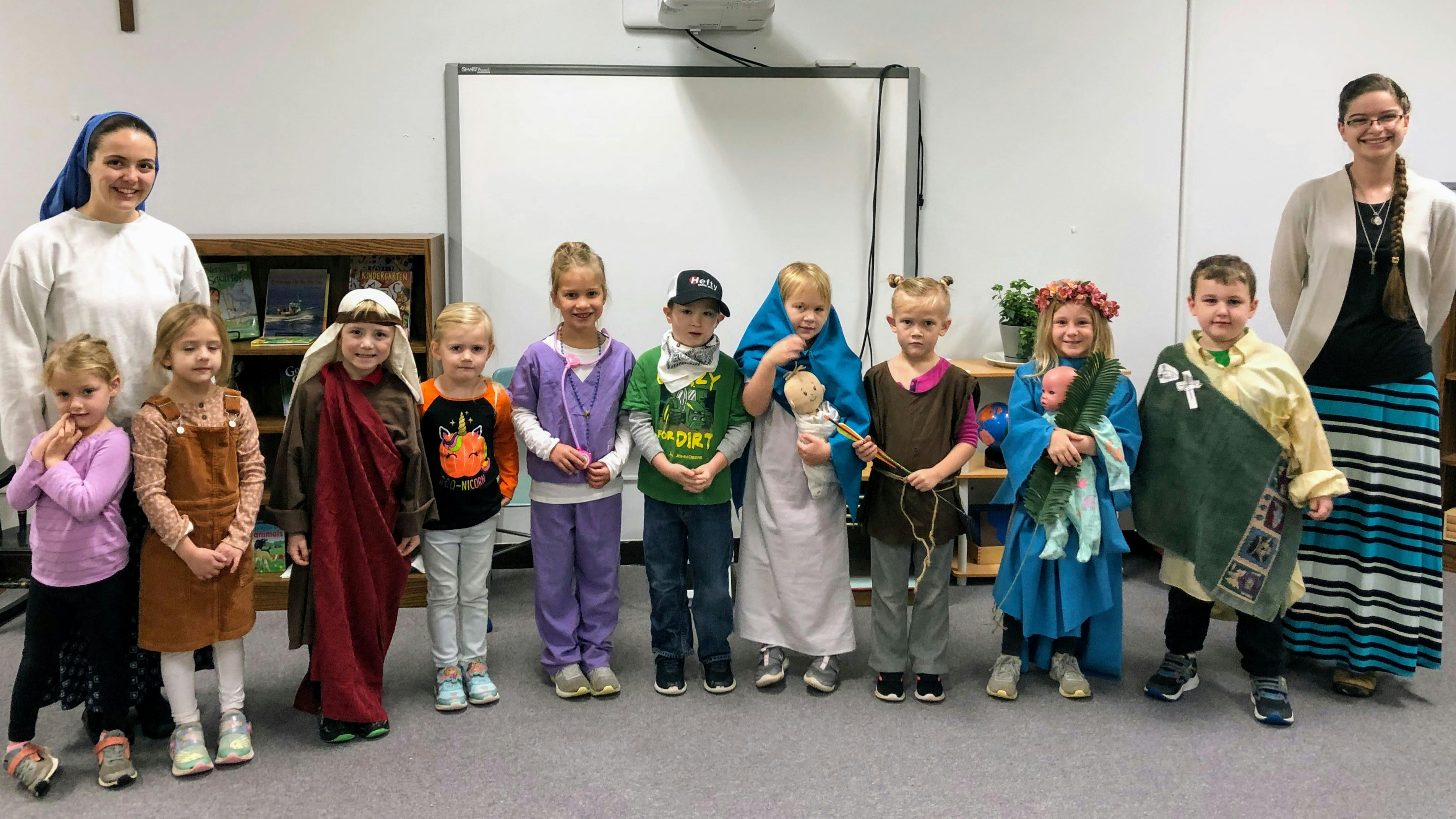 Two adults and multiple children in costumes standing in a line