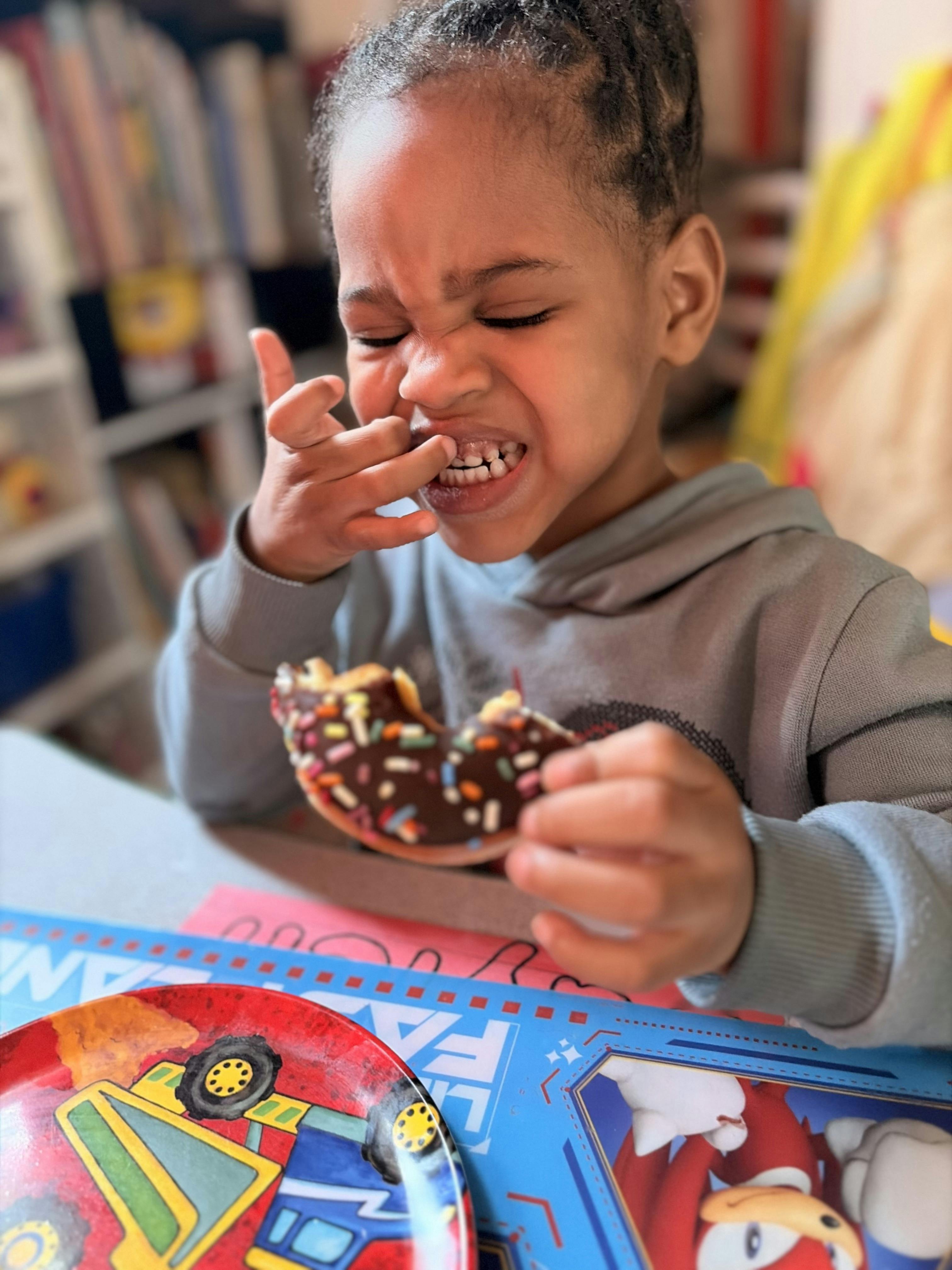 Child eating a chocolate doughnut with sprinkles