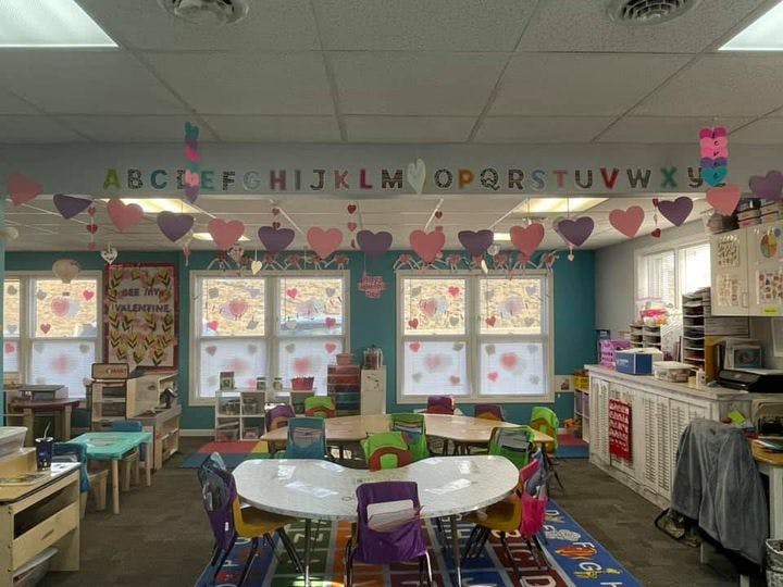 Classroom decorated with heart garlands and an ABC banner above tables and chairs