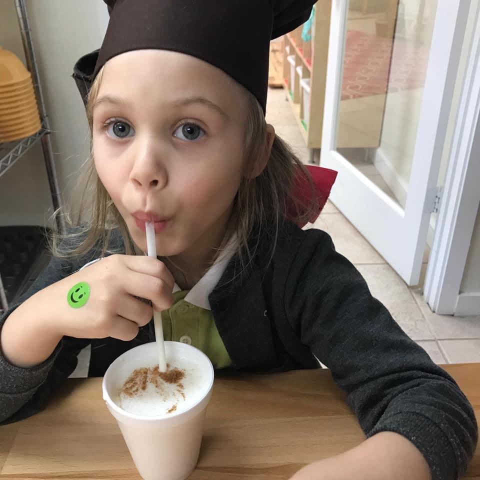 Child in a chef hat drinking from a cup with a straw