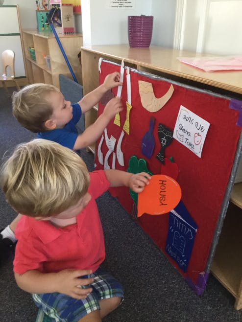 Two children playing with felt shapes on a red board