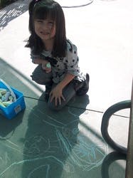 Child kneeling on a patio with chalk drawings