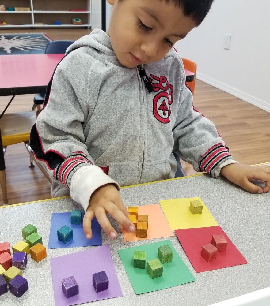 Child playing with colorful blocks on colored paper squares