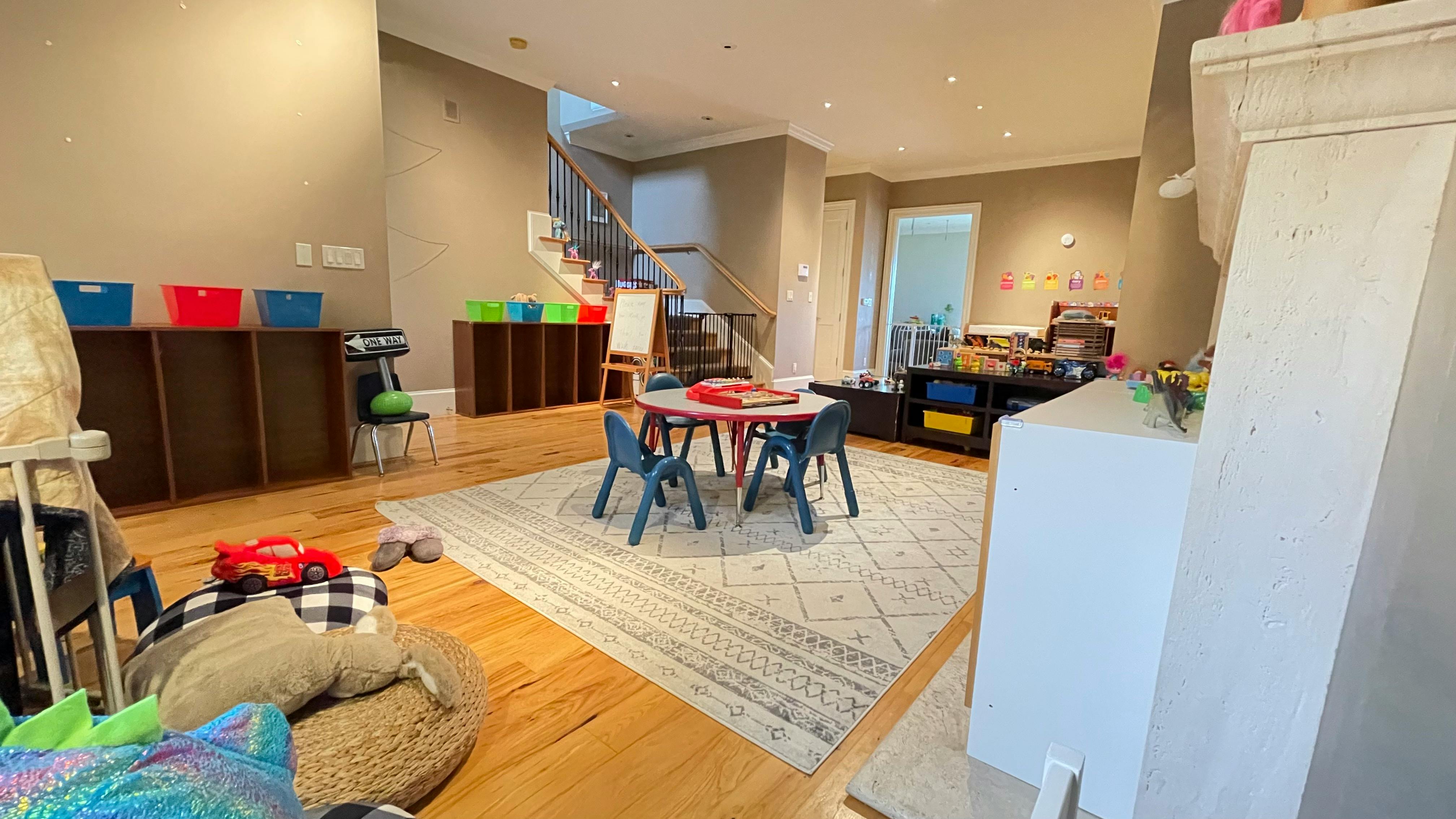 Playroom with small table and chairs on a rug, storage shelves