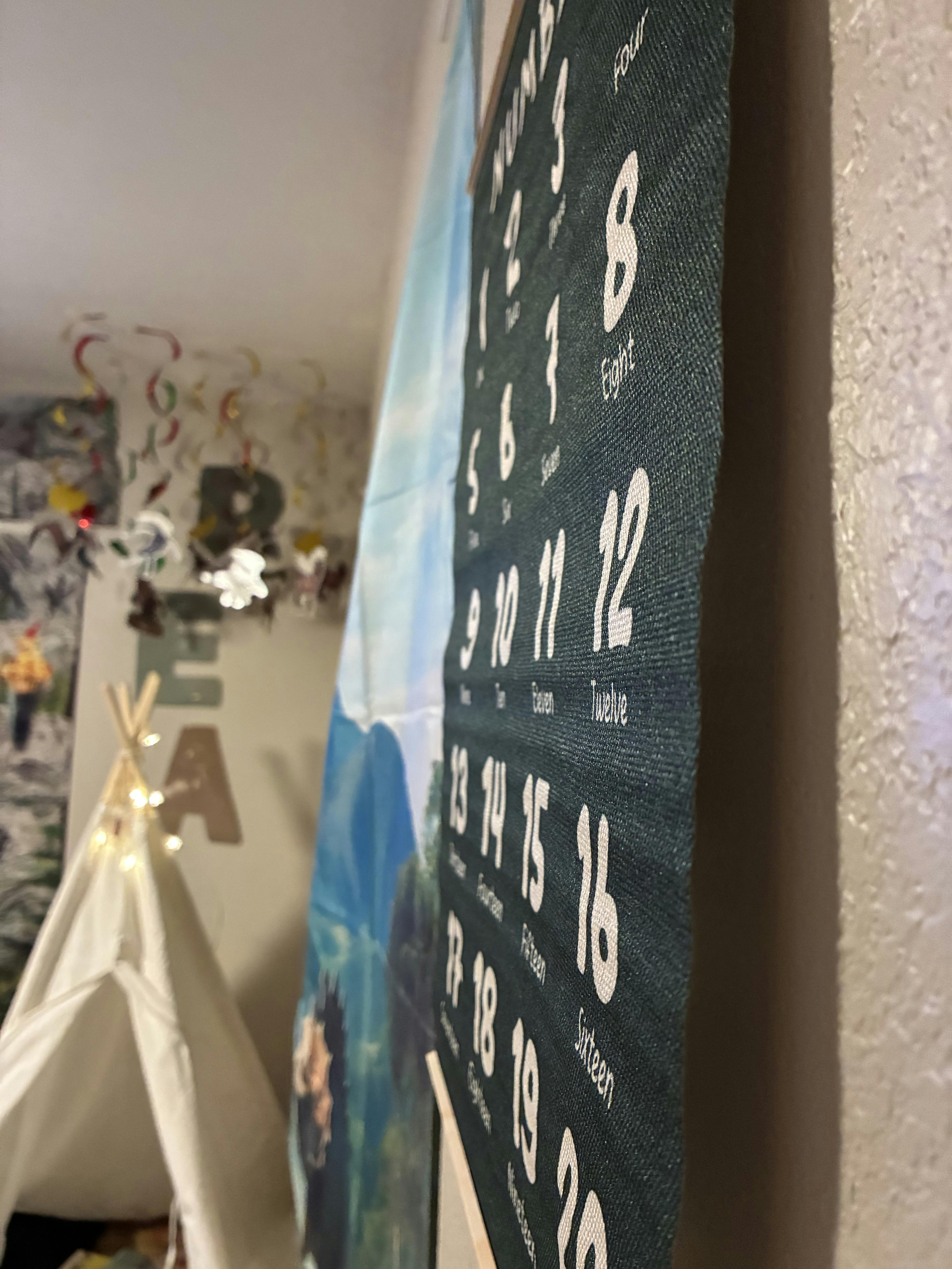 Close-up of a dark green fabric wall hanging with white numbers