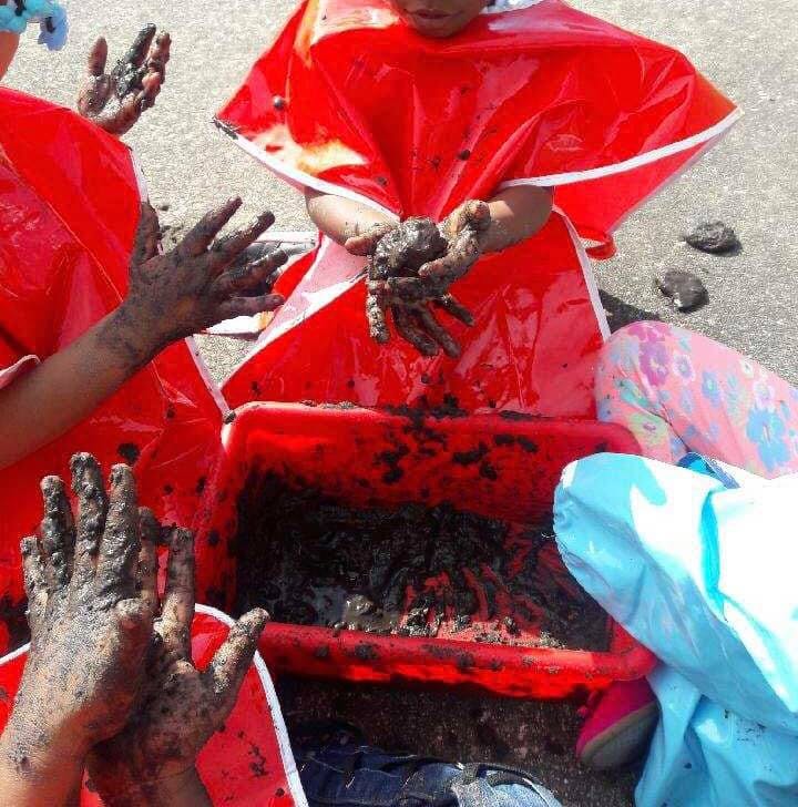 Children in red smocks playing with mud