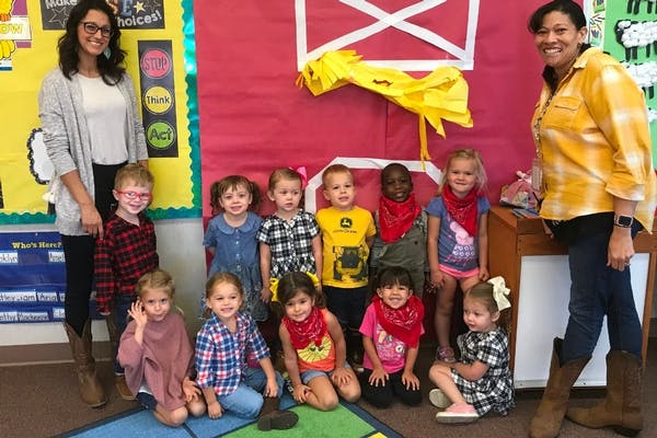 Two people with a group of children in a classroom