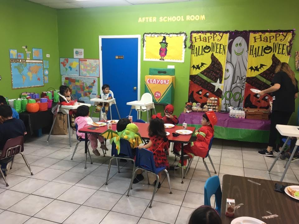 Children and an adult in a classroom with Halloween decorations