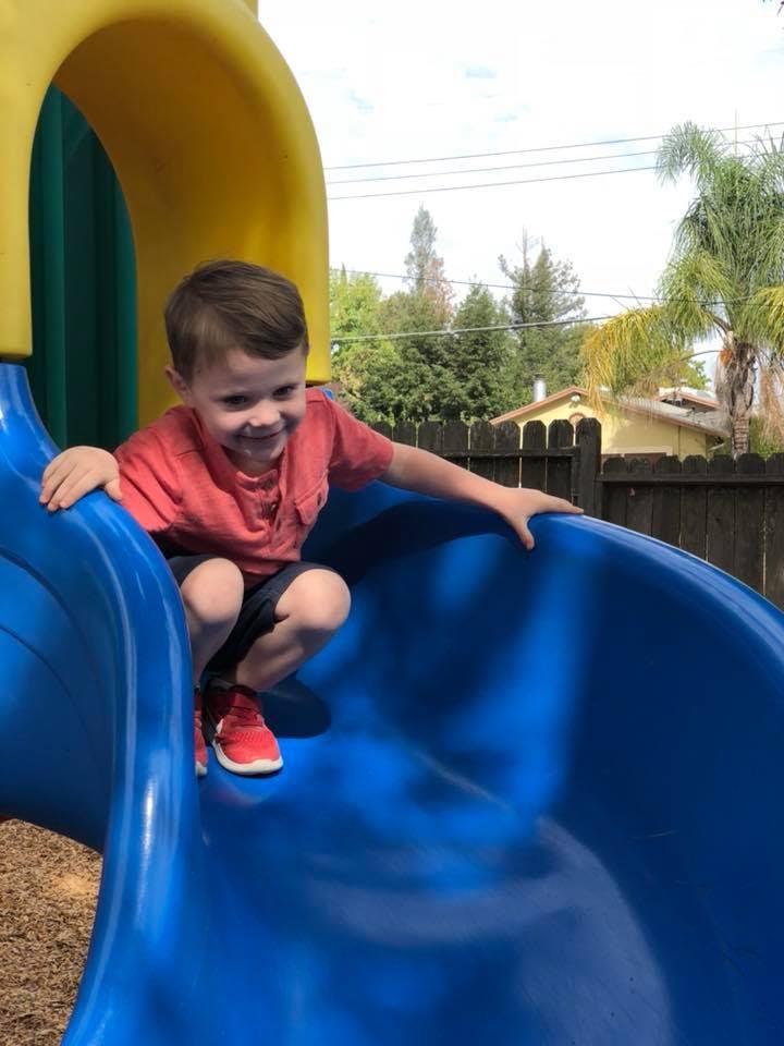 Child on a blue playground slide