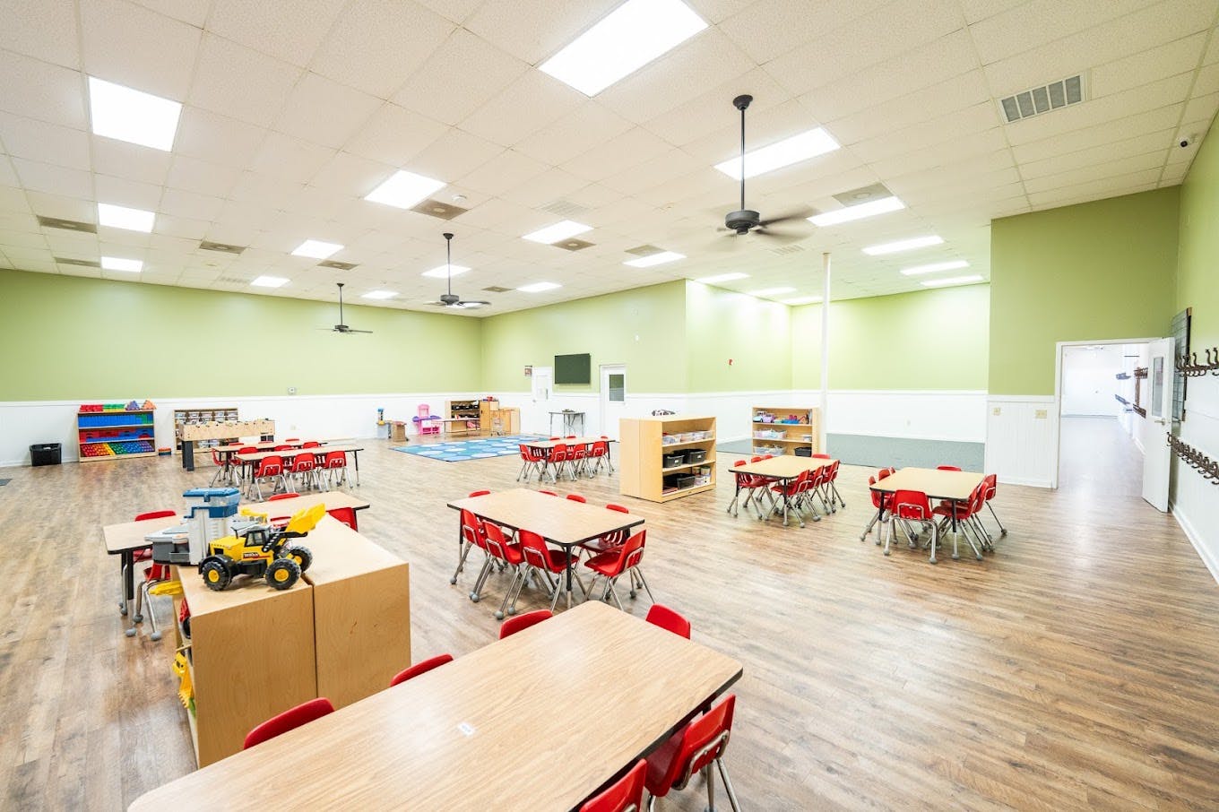 Spacious daycare classroom with small tables and chairs