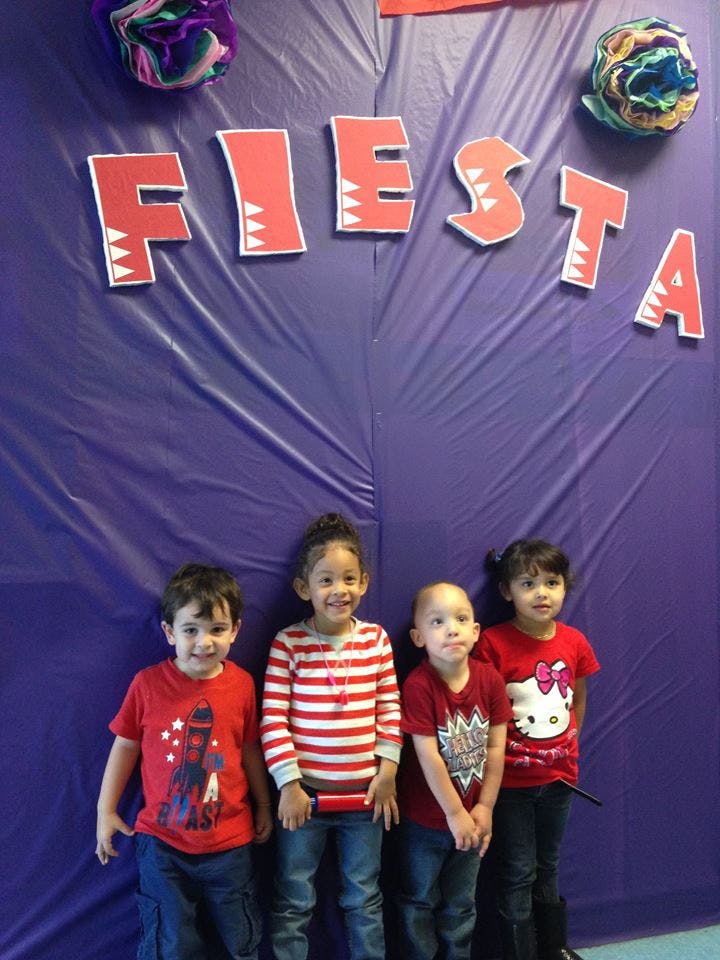 Four children standing in front of a purple background with "FIESTA" written above them