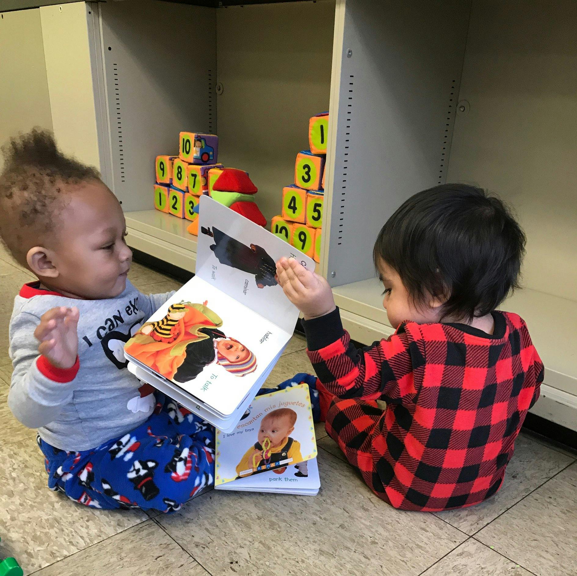 Two children sitting on the floor looking at a book together